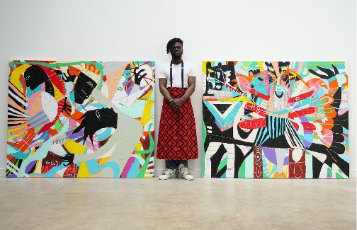 Adebayo Bolaji standing beside two of his colourful and striking works.